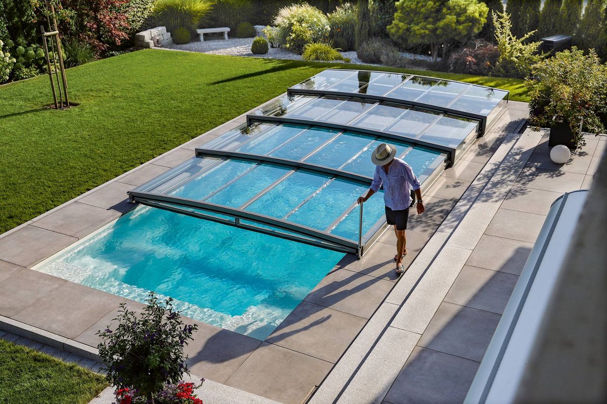Eine Person öffnet die geöffnete, schienenlose Poolüberdachung im Garten allein am Bediengriff