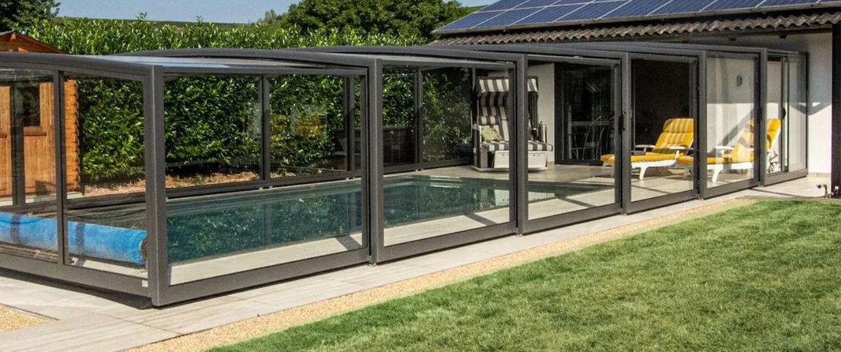 Monza – halbhohe, begehbare Poolüberdachung entlang eines Hauses mit Lounge-Bereich