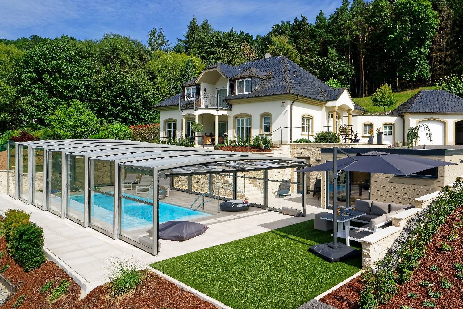 Luftaufnahme einer Villa mit langer, tonnenförmiger Paradiso-Poolüberdachung über dem Pool