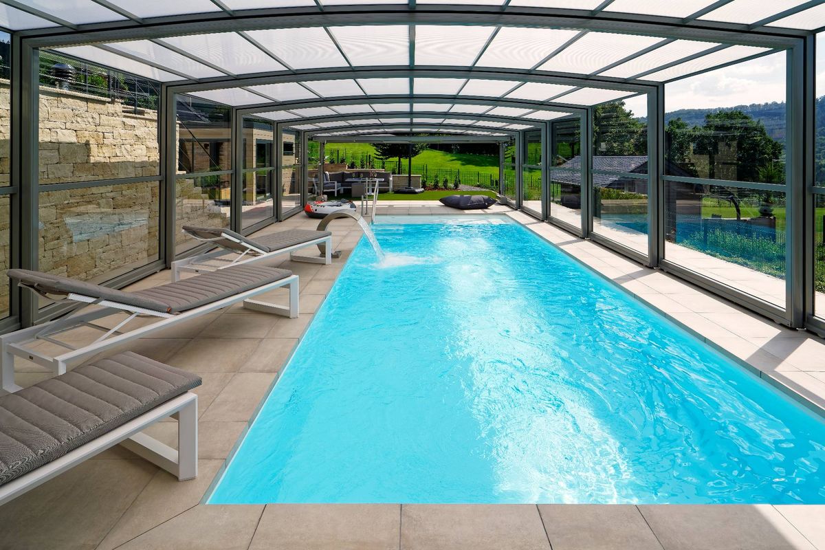 Innenansicht einer Poolüberdachung mit Liegen entlang eines beheizten Schwimmbeckens
